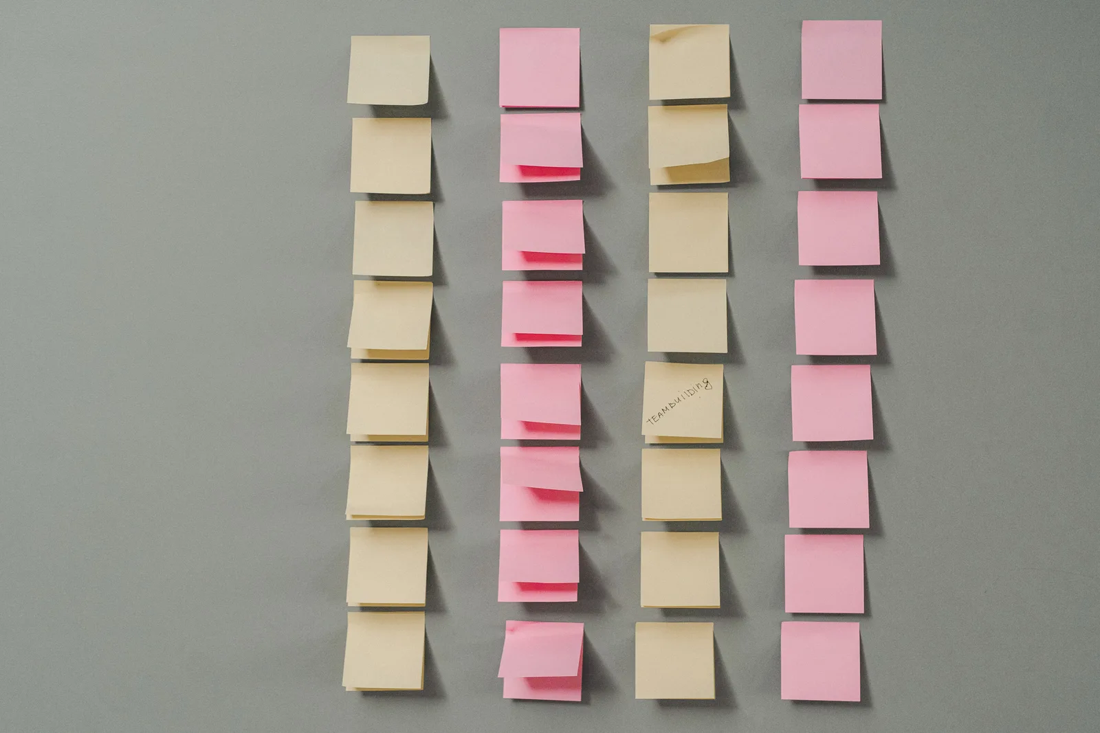 Rows of pink and yellow sticky notes on a gray background, ideal for planning concepts.